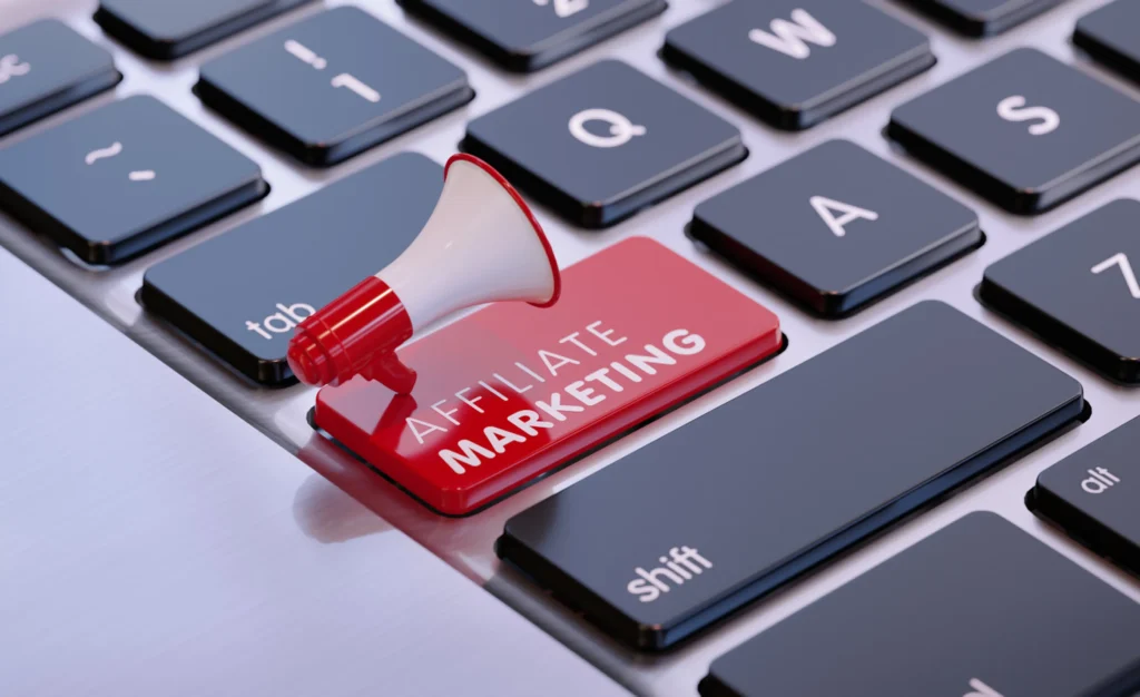 Close-up of a computer keyboard with a red key labeled "Affiliate Marketing" next to a miniature megaphone placed on top of it. The image emphasizes the concept of promoting affiliate marketing. The keys visible include "Tab," "Q," "A," "Shift," and "Ctrl".